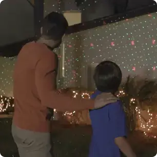 guy shows child Star Shower Ultra 9 lights on their house's exterior